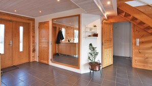 A spacious room with wooden walls and a large mirror. There is a potted plant and a shelf with decorative items. - Beautiful home in Aneby with WiFi (Aneby)