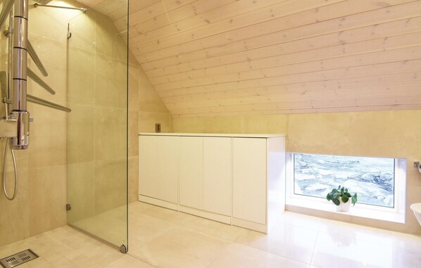 A modern bathroom with a glass shower enclosure, a white cabinet, and a window with a view of a snowy landscape.