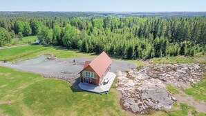A single-story house with a red roof, surrounded by a large forest and a small pond. - Beautiful home in Aneby with WiFi (Aneby)