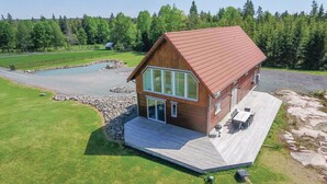 A wooden cabin with a red roof, large windows, and a stone foundation. - Beautiful home in Aneby with WiFi (Aneby)