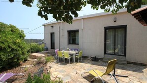 Eine Terrasse mit Tisch und Stühlen, ein gelber Stuhl und ein Steinboden.