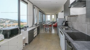 Eine moderne Küche mit Stadtblick, großen Fenstern und einer Essecke mit einem roten Stuhl.