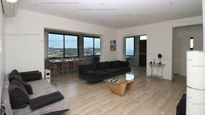 Ein modernes Wohnzimmer mit einer Couch, einem Glastisch und einem Essbereich mit Tisch und Stühlen.
