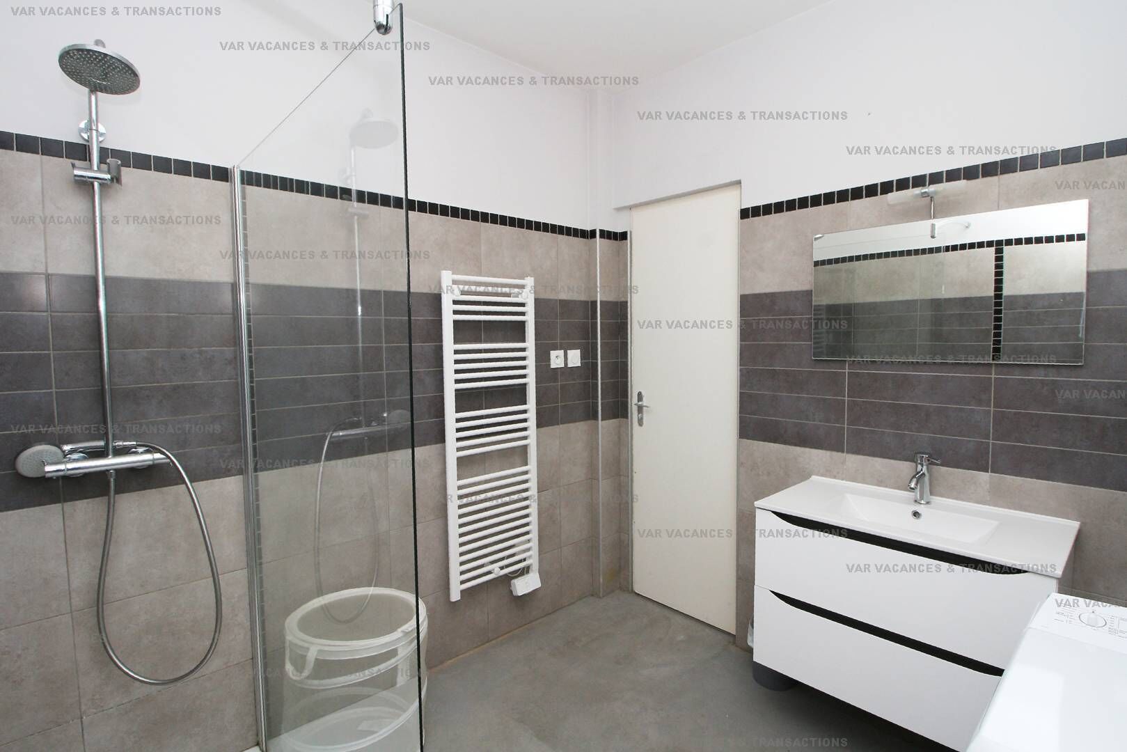 Ein modernes Badezimmer mit Dusche, einer separaten Toilette mit Glaswand und einem Waschbecken mit Spiegel.