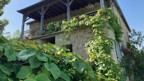 Un bâtiment en pierre doté d’un balcon en bois et d’un toit recouvert de tuiles rouges.