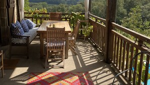 Un espace extérieur aménagé, abrité et doté de tables et de chaises, d’un tapis à motifs et d’une vue sur la campagne.