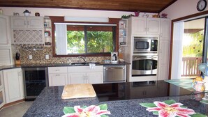 A kitchen with a granite countertop, stainless steel appliances, and a window with a view of greenery. - Venetian Shores Escape! Heated Pool, 3BR, 70ft Dock, Dog-Friendly! (Islamorada)