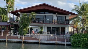 A two-story waterfront property with a balcony, a dock, and a view of the water. - Venetian Shores Escape! Heated Pool, 3BR, 70ft Dock, Dog-Friendly! (Islamorada)