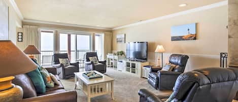 A spacious living room with leather sofas, a television, and a dining area.
