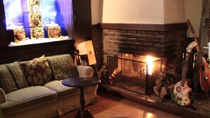 A cozy living room with a fireplace, a sofa, a television, and guitars. - Fujikawaguchiko Crescendo (Fujikawaguchiko)