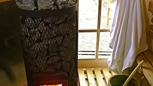 Una estufa de leña con fuego, una ventana que ofrece vistas al exterior y una toalla colgada en la pared.