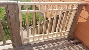 Une terrasse en bois avec une balustrade blanche, un sol à carreaux et une vue sur une pelouse.