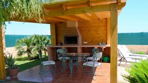 Un patio exterior con un horno de ladrillo, una mesa con sillas y vistas al mar.