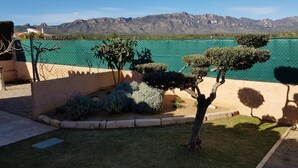 Un jardín ajardinado con setos cuidados y una vista despejada de un paisaje montañoso al fondo.