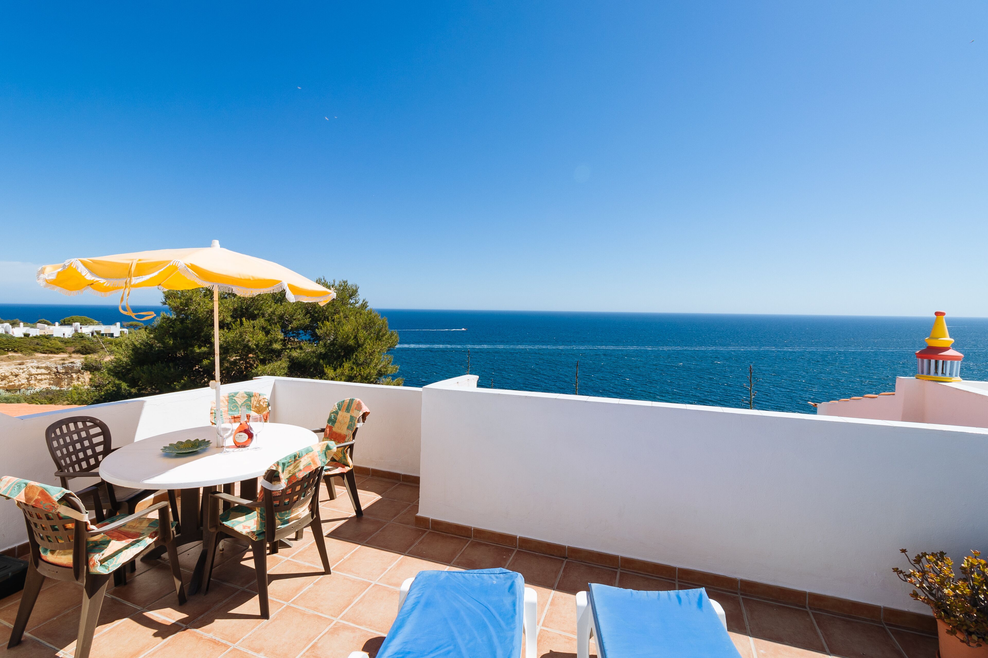 Una terrazza con tavolo, sedie e ombrellone vista mare.