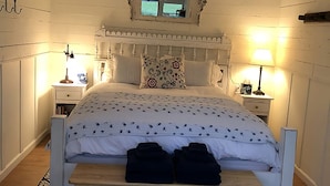 Un dormitorio con cama, lámparas de noche, ventilador de techo y una alfombra estampada.