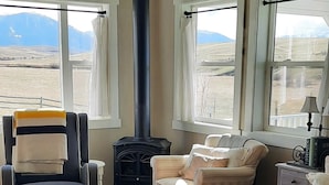 Un salón con un ventanal grande, chimenea, ventilador de techo y sofá.