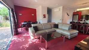 A modern living room with a sectional sofa, a glass coffee table, and a dining area with a table and chairs. - De Vine Martinborough 14a Cologne St (Martinborough)