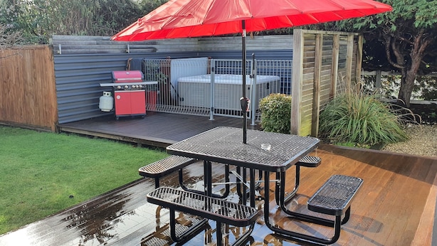 A patio with a red umbrella, a barbecue grill, and a hot tub. - De Vine Martinborough 14a Cologne St (Martinborough)