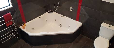 A modern bathroom with a freestanding bathtub, a toilet, and a towel rack with a red towel.