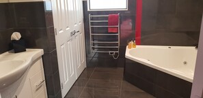 A modern bathroom with a white sink, a bathtub, and a towel rack with a red towel.