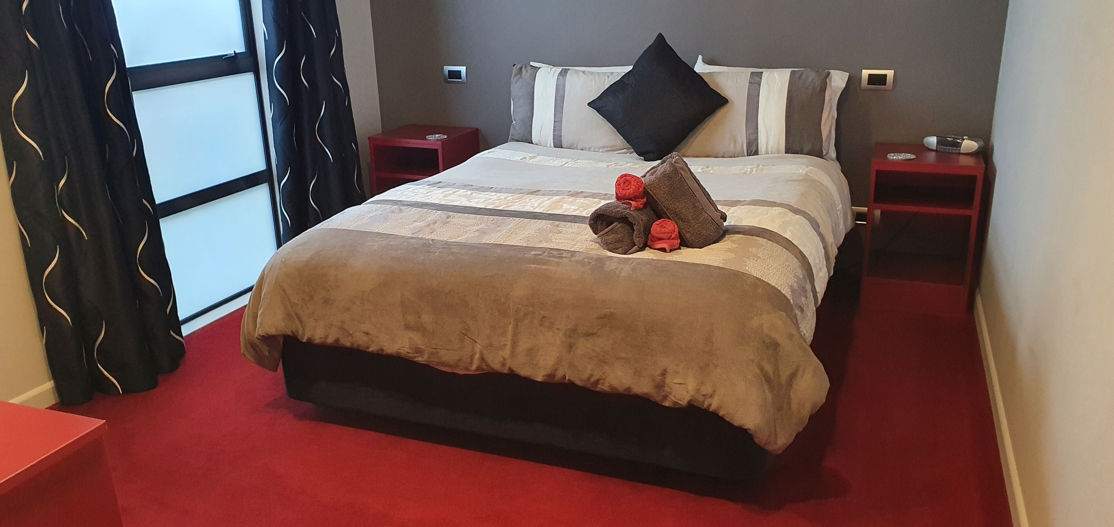 A neatly made bed with a brown bedspread, two pillows, and a folded towel on the side.