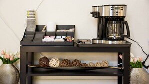 A coffee station with a coffee maker, a tray with cups, and a shelf with decorative items.
