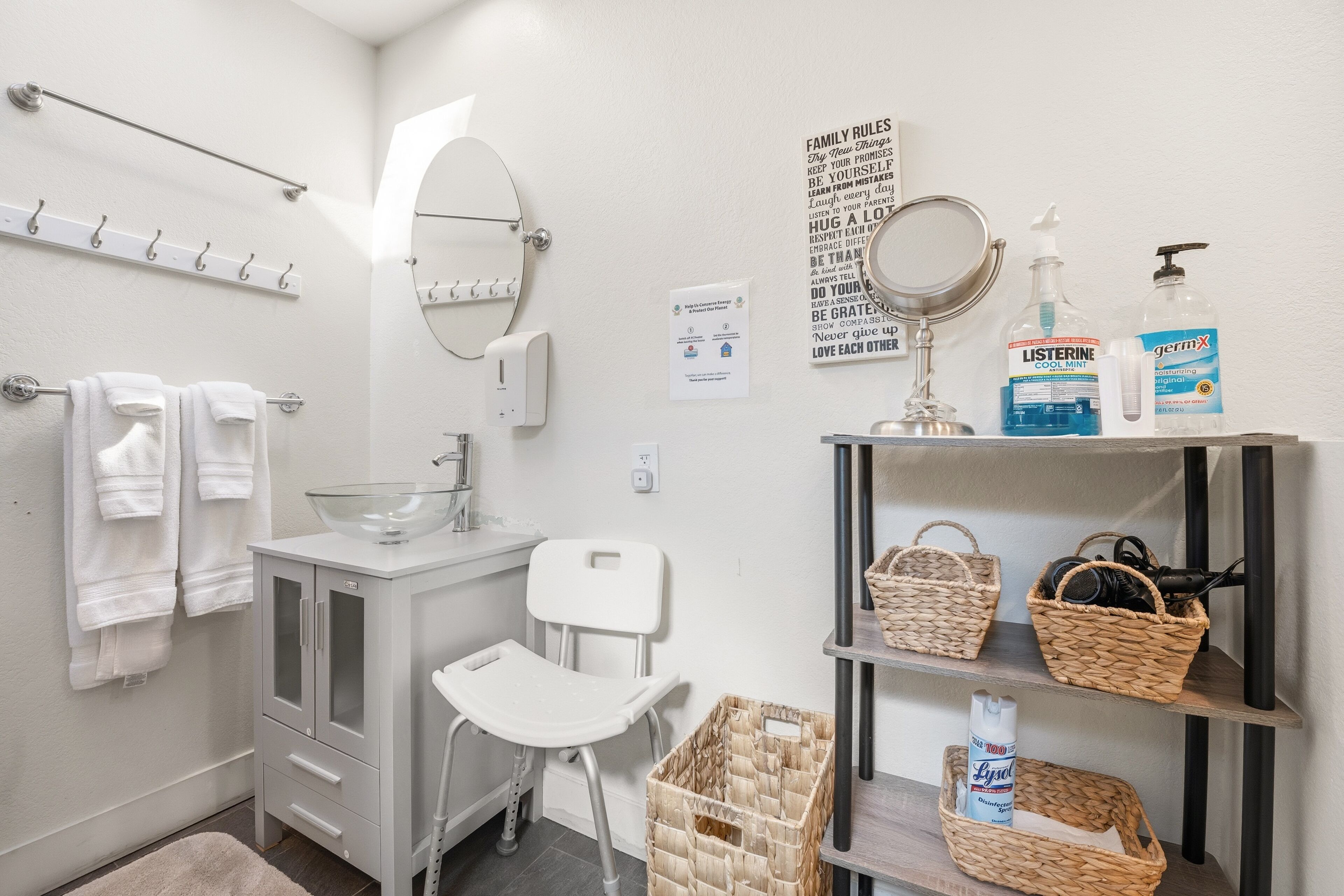 A bathroom with a white sink, mirror, towel rack, and shelves with baskets and toiletries.