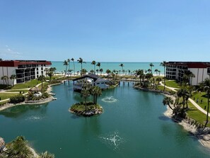 Ein Resort mit einem zentralen Wasserspiel, Palmen und Blick auf den Ozean.