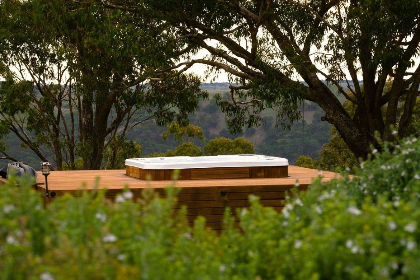 A hot tub on a wooden deck surrounded by trees.