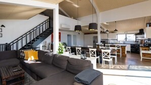 A spacious living area with a large sofa, a dining table with chairs, and a kitchen area with modern appliances. - Abercrombie Ridge - Lux BARN and Spa Retreat - Pet-friendly (Curraweela)