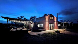 A modern house with a covered patio area, a large window, and a visible chimney. - Abercrombie Ridge - Lux BARN and Spa Retreat - Pet-friendly (Curraweela)
