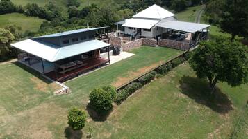 A large house with a spacious patio, a covered outdoor area, and a well-maintained lawn.