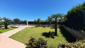 A well-maintained outdoor area with a paved walkway, palm trees, and a variety of shrubs and flowers. - Mediterranean villa - 150 meters from the promenade of Cefalu (Campofelice di Roccella (Pa))