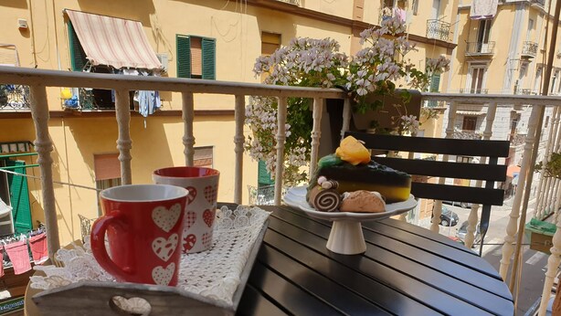 A balcony with a table set for breakfast, featuring a cake, cookies, and two heart-patterned mugs. - HOLIDAY HOME Central station, business center, central Naples, Mary's Sweet home (Napoli)