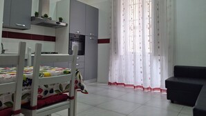 A modern kitchen with grey cabinets, a built-in oven, and a dining area with a table and chairs. - HOLIDAY HOME Central station, business center, central Naples, Mary's Sweet home (Napoli)