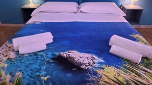 A neatly made bed with a blue and white bedspread, two bedside lamps, and a blue headboard. - HOLIDAY HOME Central station, business center, central Naples, Mary's Sweet home (Napoli)