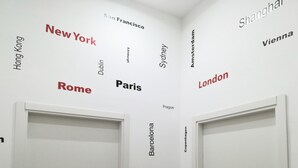 A room with two white doors and a wall with city names in various fonts and colors. - HOLIDAY HOME Central station, business center, central Naples, Mary's Sweet home (Napoli)