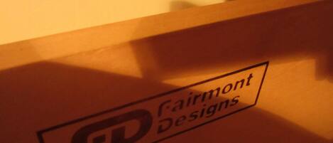 A logo with the text "Fairmont Designs" on a wooden surface.