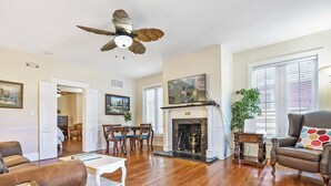 Un salon spacieux doté de planchers en bois franc, d’une cheminée, d’un ventilateur de plafond et d’un coin salon confortable.