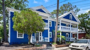 Une maison à deux étages, avec une façade bleue, un porche à l’avant et une voiture garée devant.