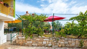 A stone wall with a vineyard, outdoor seating, and a building with a yellow railing. - Beautiful apartment in Pula with WiFi (Pula)