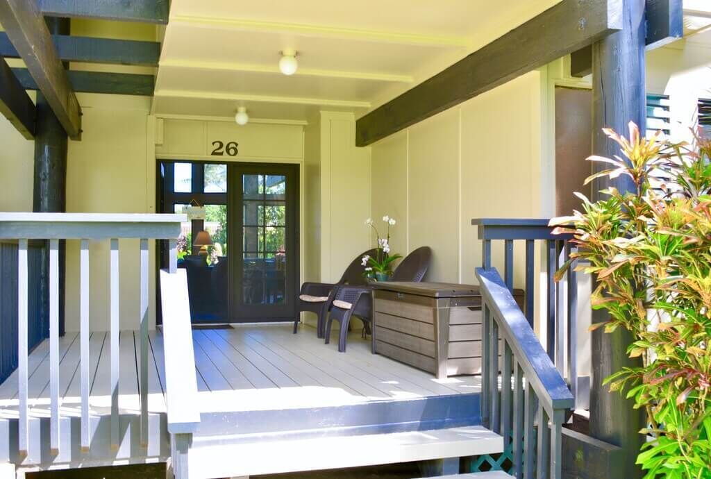 A covered outdoor area with a wooden deck, a reception desk, and two chairs.