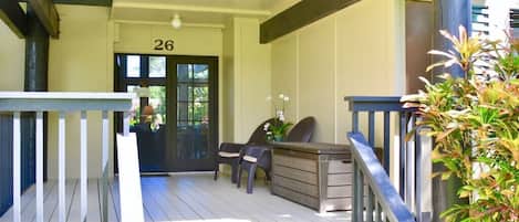A covered outdoor area with a wooden deck, a reception desk, and two chairs.