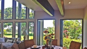 Un comedor con una mesa redonda, sillas de mimbre y un jarrón con girasoles.