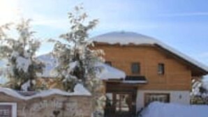 A wooden cabin with a snow-covered roof, surrounded by trees and a clear sky. - COEUR DES ALPES - Sabot de Vénus (Taninges)
