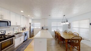 Una cocina moderna con armarios blancos, electrodomésticos de acero inoxidable y una isla central.