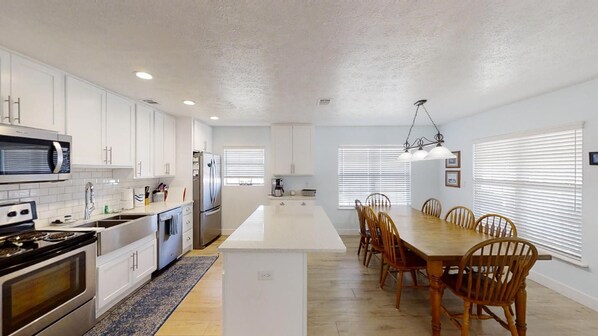 A modern kitchen with white cabinets, stainless steel appliances, and a central island.