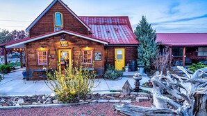 A rustic wooden building with a red roof, a guest lounge, and outdoor seating. - The Loubird Inn (Escalante)