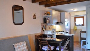 A cozy living room with a sofa, a dining table with chairs, and a kitchen area with a stove and cabinets. - Cozy House with Pool & Tennis, Near Beach, Sleeps 6 - Bormes-les-Mimosas (Bormes-les-Mimosas)